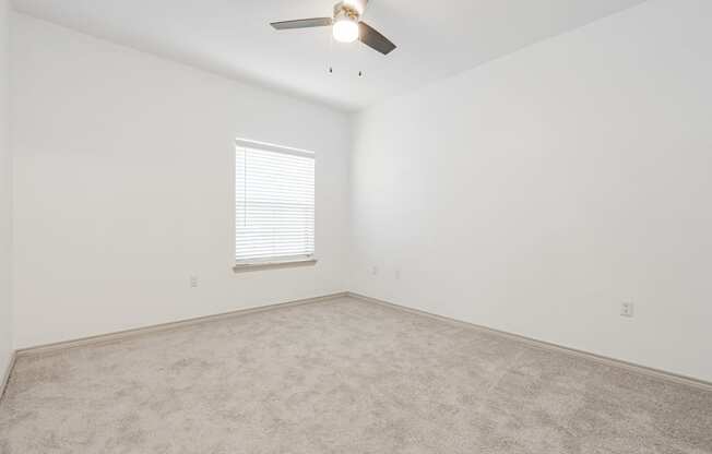 an empty room with a ceiling fan and a window