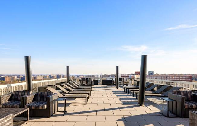 a roof top lounge area with chairs and tables and a view of the city