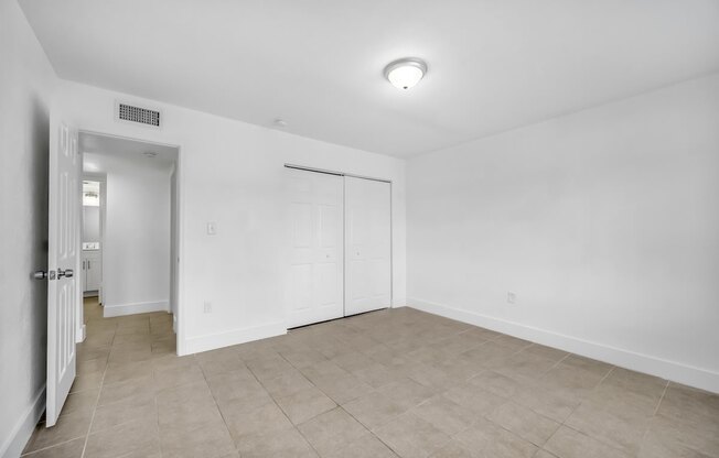 the living room of an apartment with white walls and a tiled floor