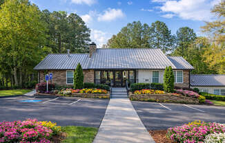 Our leasing office exterior filled with vibrant flowers and trees on a spring morning.