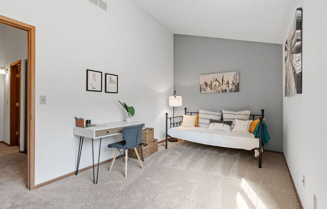 a bedroom with a white bed and a desk with a chair