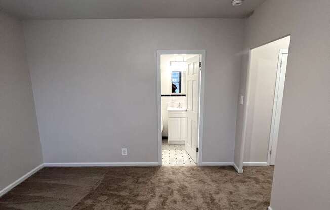 A room with a carpeted floor and a doorway leading to another room.