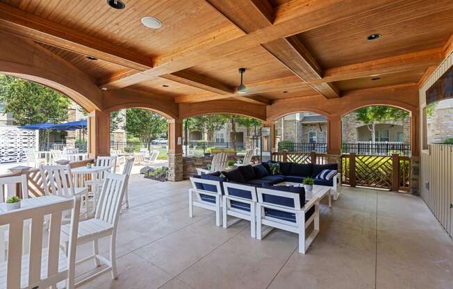 a covered patio with a wooden ceiling and white furniture