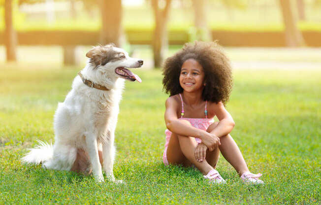 a girl sitting on the grass with her dog