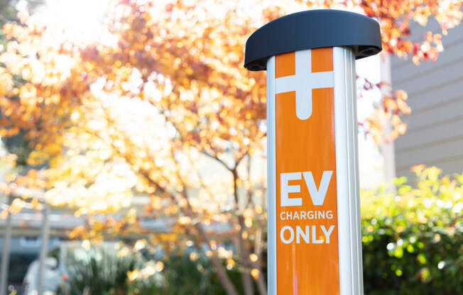 an ev charging station in front of a house with trees in the background