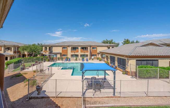 A sunny day at a residential complex with a pool and a fence.