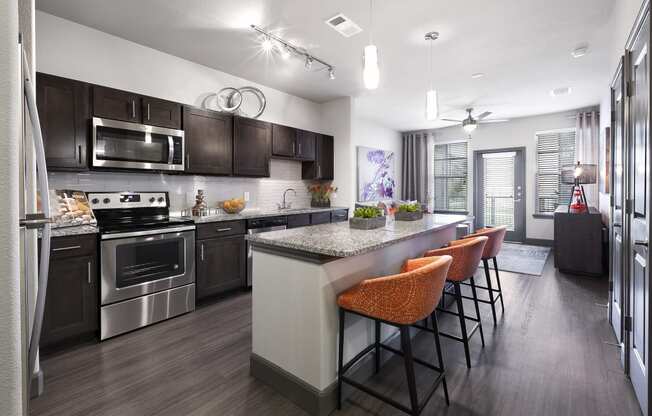 a kitchen with stainless steel appliances and a large island with chairs