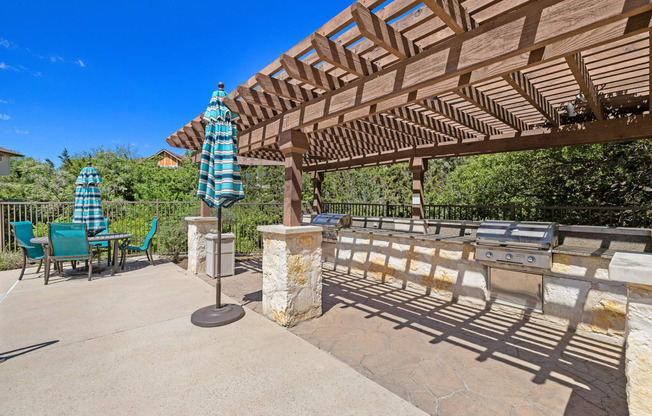 a patio with a pergola and table with umbrellas