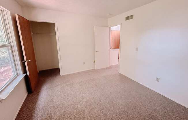 a bedroom with a carpeted floor and a door to a closet