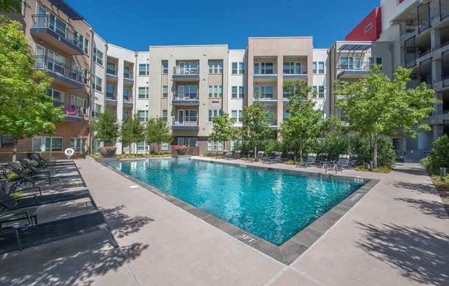 an apartment pool with an apartment building in the background at South Side Flats, Dallas, TX