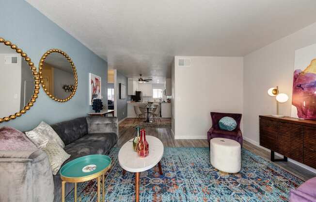 Living Room with Blue Pattern Rug, White Table, Gray Sofa, Purple Chair and Round Wall Mirrors