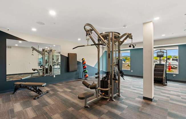 A gym with a variety of equipment including a treadmill, a bench, and a mirror.