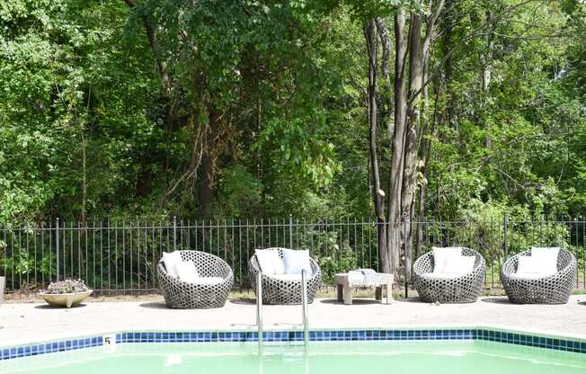 the pool is next to a fence and some chairs