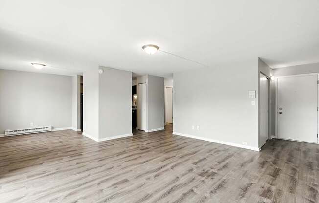 A spacious room with wooden flooring and white walls.