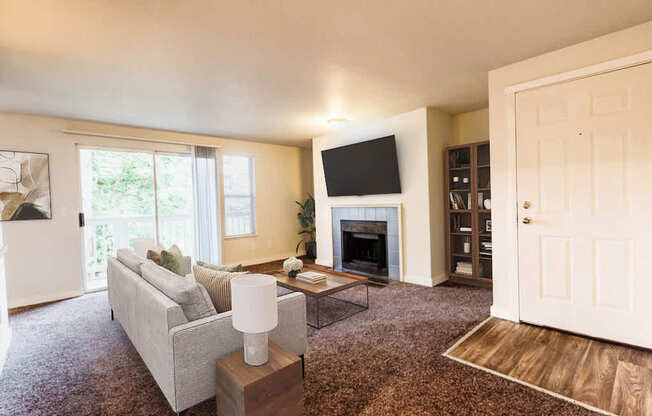 A living room with a grey couch, a fireplace, and a television.