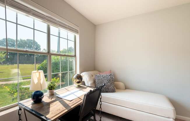 a home office with a large window and a desk with a chair and a lamp