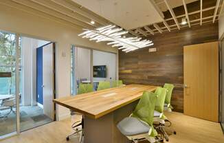 A conference room with a long table and green chairs.