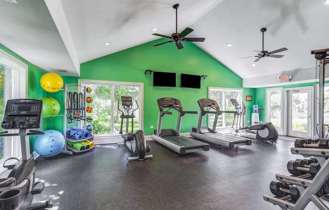 Apartments in Geneva, IL for Rent- Ashford at Geneva- A gym with a green wall and various exercise equipment.