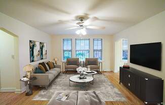 a living room with a ceiling fan and a tv on the wall at 3101 Pennsylvania apartments in washington dc
