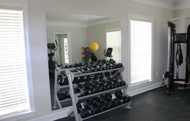 A gym room with a mirror, weights, and exercise equipment.