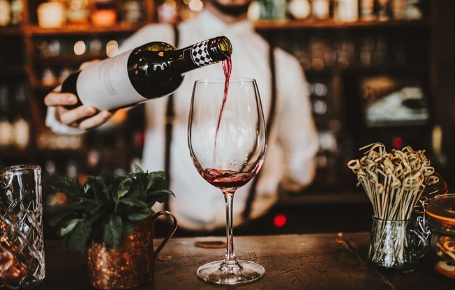 a man pouring wine into a glass in a bar at District at Riverside Apartments, Tennessee, 37406