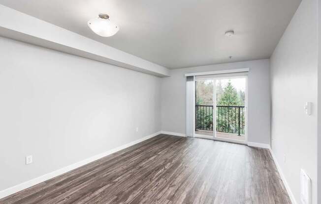 A room with a sliding glass door leading to a balcony with a railing.