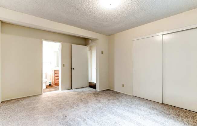 an empty living room with a closet and a door to a hallway