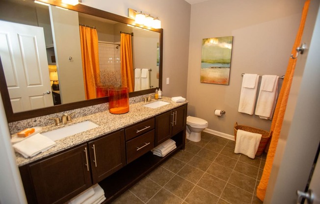 a bathroom with two sinks and a toilet and a large mirror