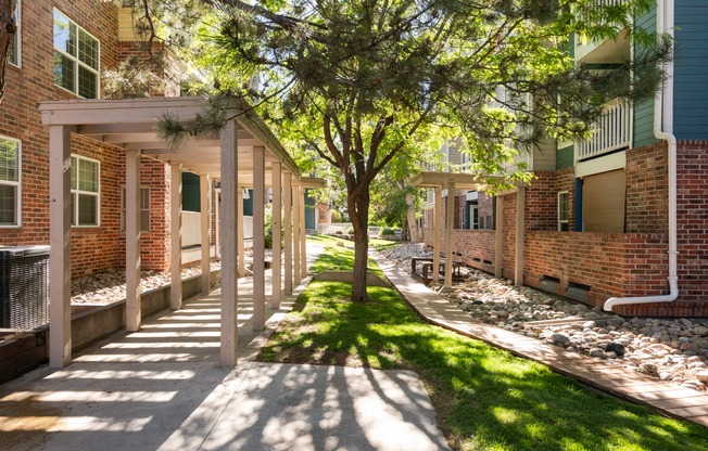 a sidewalk in front of a brick building with trees