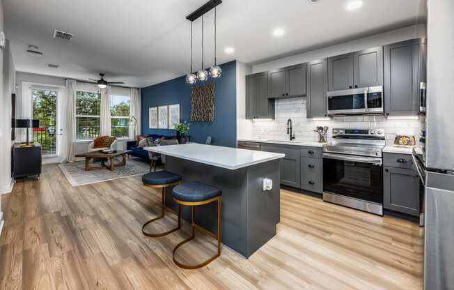 a kitchen and living room with a large island with three stools at The Alibi at Lake Lilly, Florida