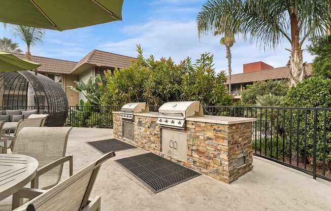 A patio with a stone BBQ and chairs.