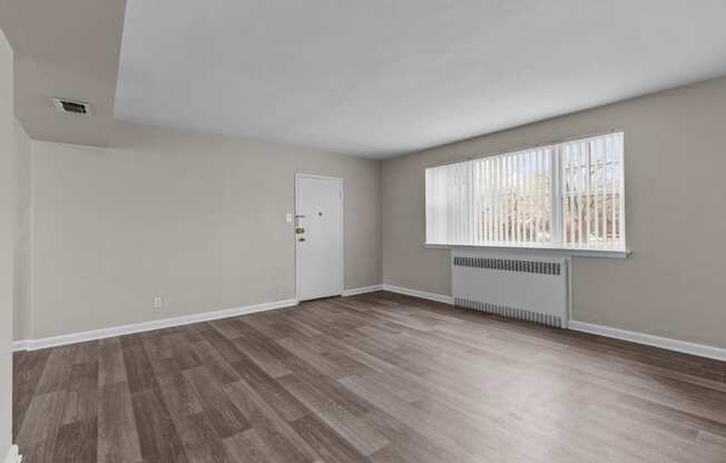 the living room of an empty house with wood flooring and a window