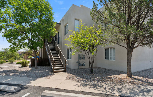 a white house with stairs and trees in front of it