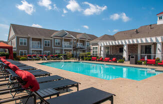 a swimming pool with chaise lounge chairs and a building in the background