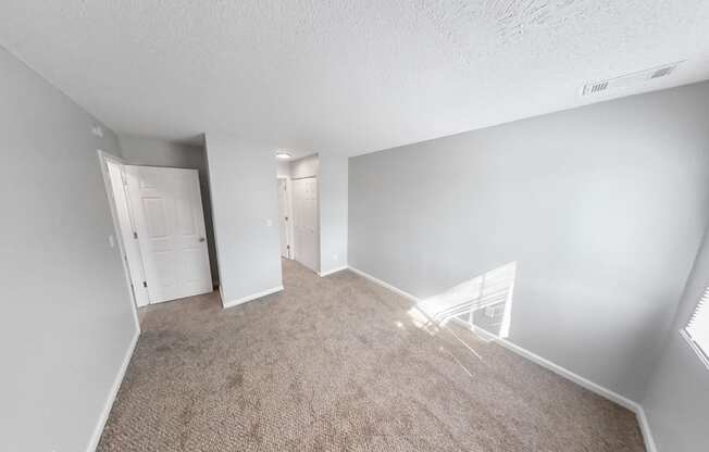 the living room of an apartment with a carpeted floor and white walls