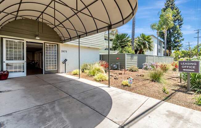The image shows a leasing office with a curved roof and a garden in front.