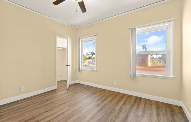 an empty living room with wood floors and a ceiling fan