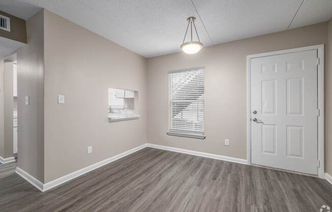 A room with a white door, a window with blinds, and a light hanging from the ceiling.