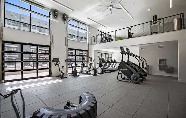 A gym with treadmills, elliptical machines, and weights.