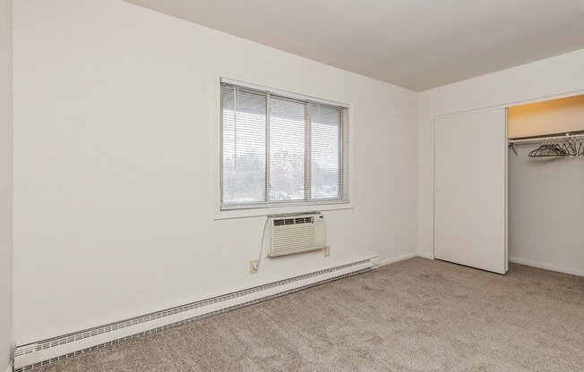 an empty room with a window and a closet