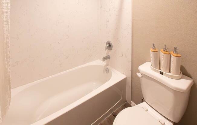 A white toilet with a toilet paper holder with four rolls of toilet paper.