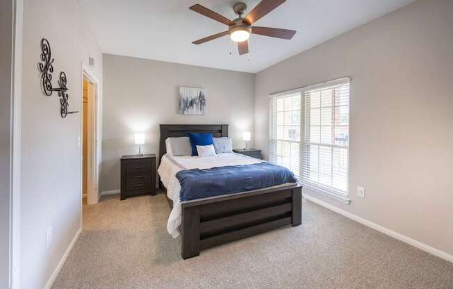A bedroom with a bed, nightstand, and a ceiling fan.