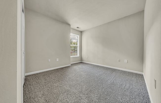 an empty room with carpet and a window