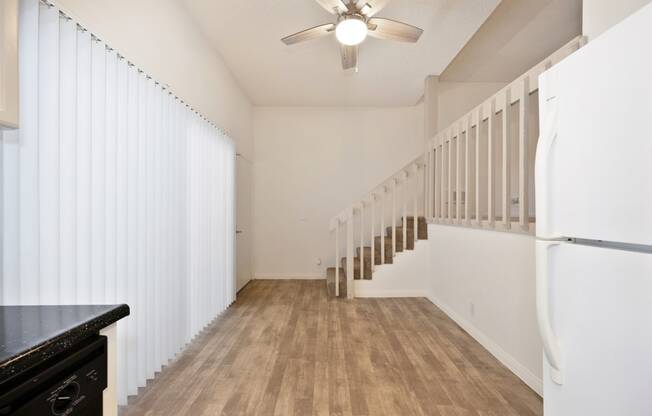 an open kitchen and living room with white walls and wood floors