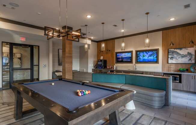 a pool table in a clubhouse with a bar and tv