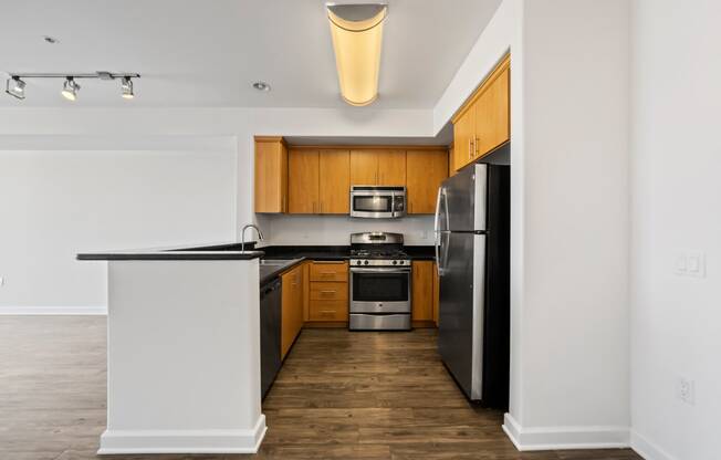 an empty apartment kitchen with black countertops and stainless steel appliances