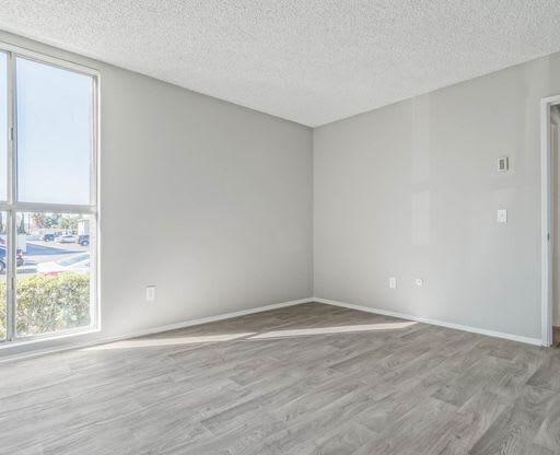 an empty living room with a large window and wooden floors at The Arches Apartments, California, 92021