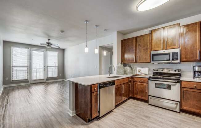 Empty kitchen with wooden cabinets and stainless steel appliances at The Atlantic Highland Park, Dallas, 75209