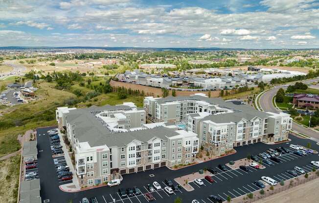 A large apartment complex with a parking lot in front.