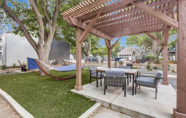 A wooden pergola with a hammock under it.